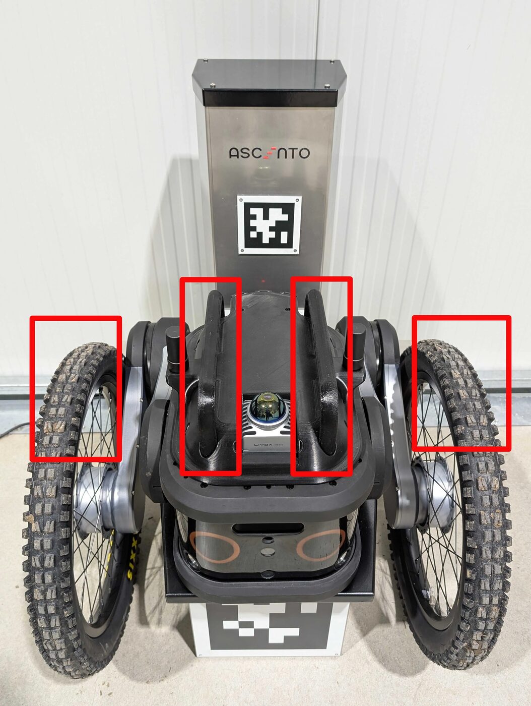 Two people carrying the Ascento robot together, each supporting one wheel and one handle
